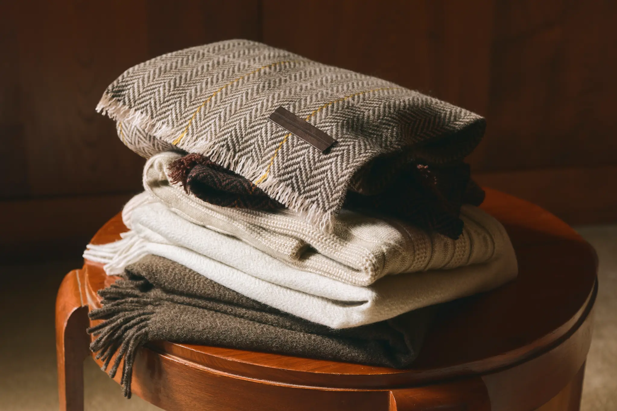 ZEGNA FW26 scarves in different colours and fine materials displayed on a stool