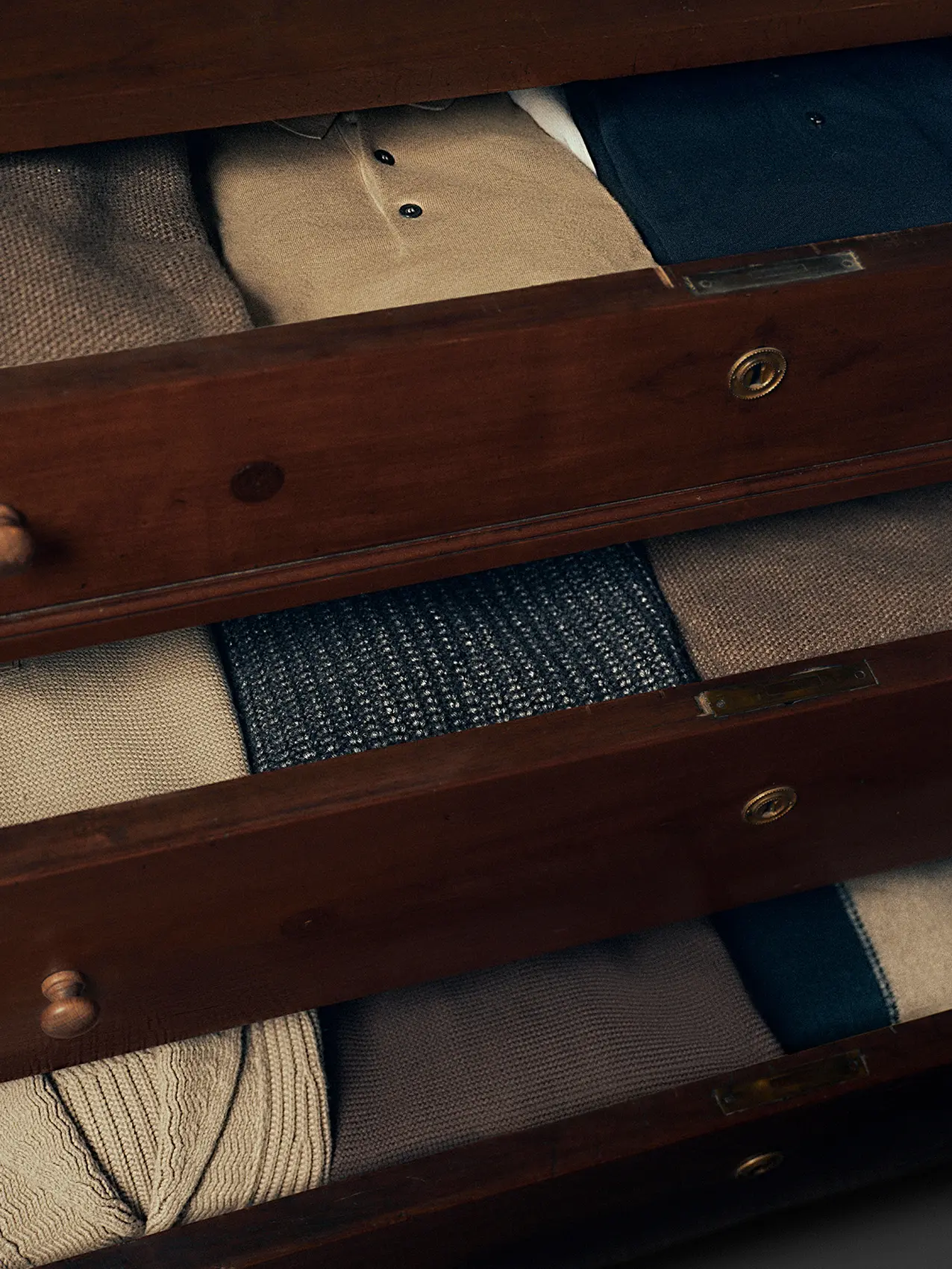 採用優質羊毛和奢華布料製作的 ZEGNA 男裝毛衣疊放在木製衣櫃。