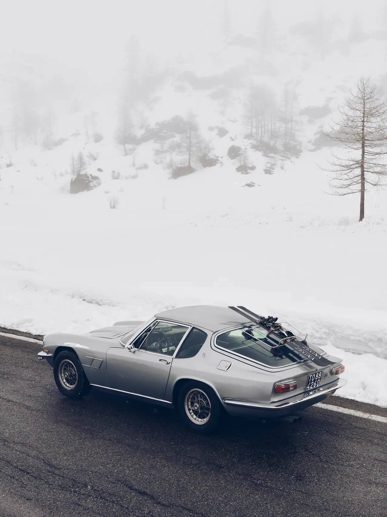 2025 年秋冬系列广告中雪景下的 ZEGNA（杰尼亚）滑雪板与跑车。