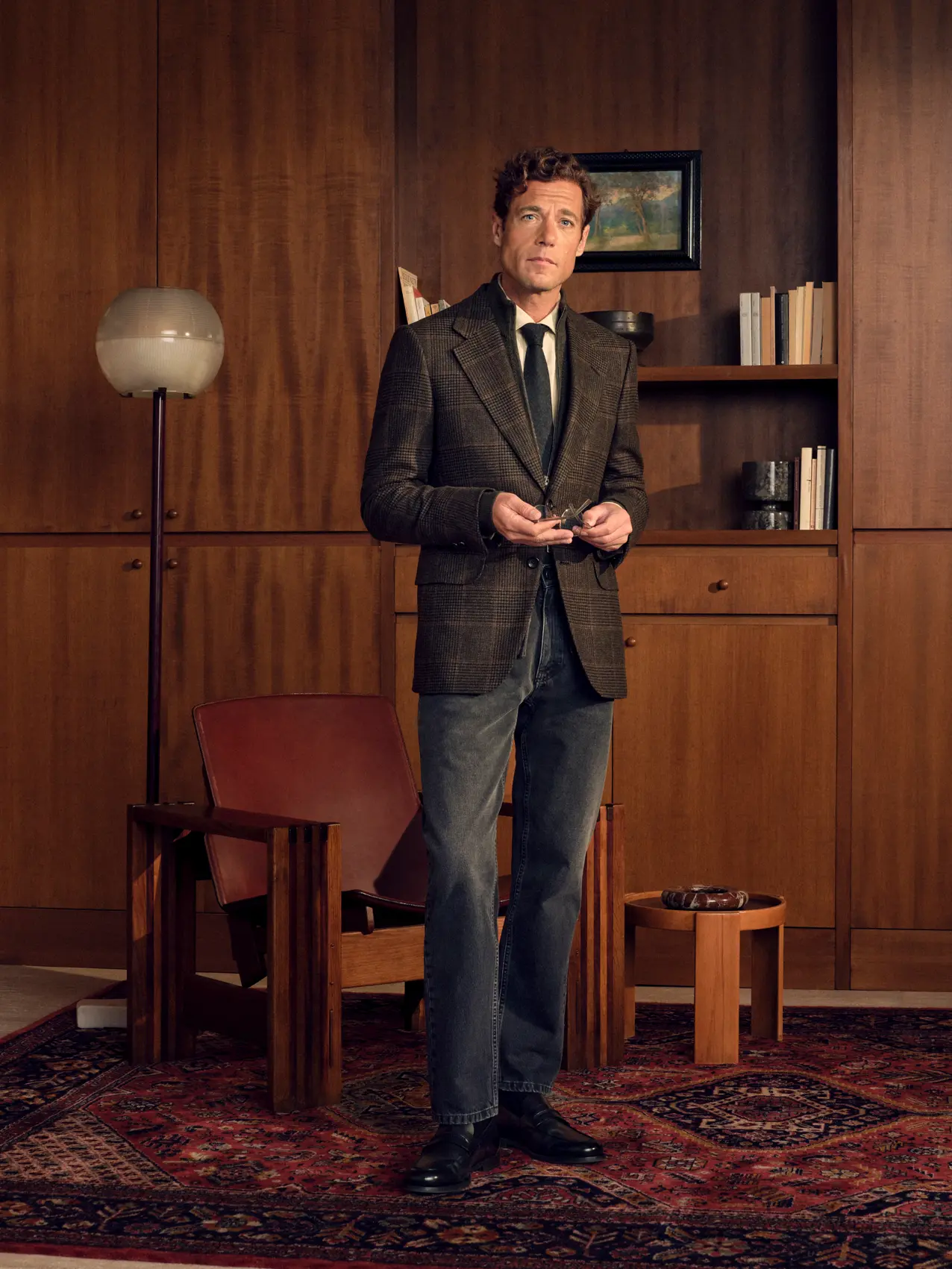 Man in a refined look wearing the Oasi Cashmere Jacket in dark olive green and black Prince of Wales with a wool jacquard tie and pure cotton Roccia denim in dark grey, from the ZEGNA Fall/Winter 2026 collection.