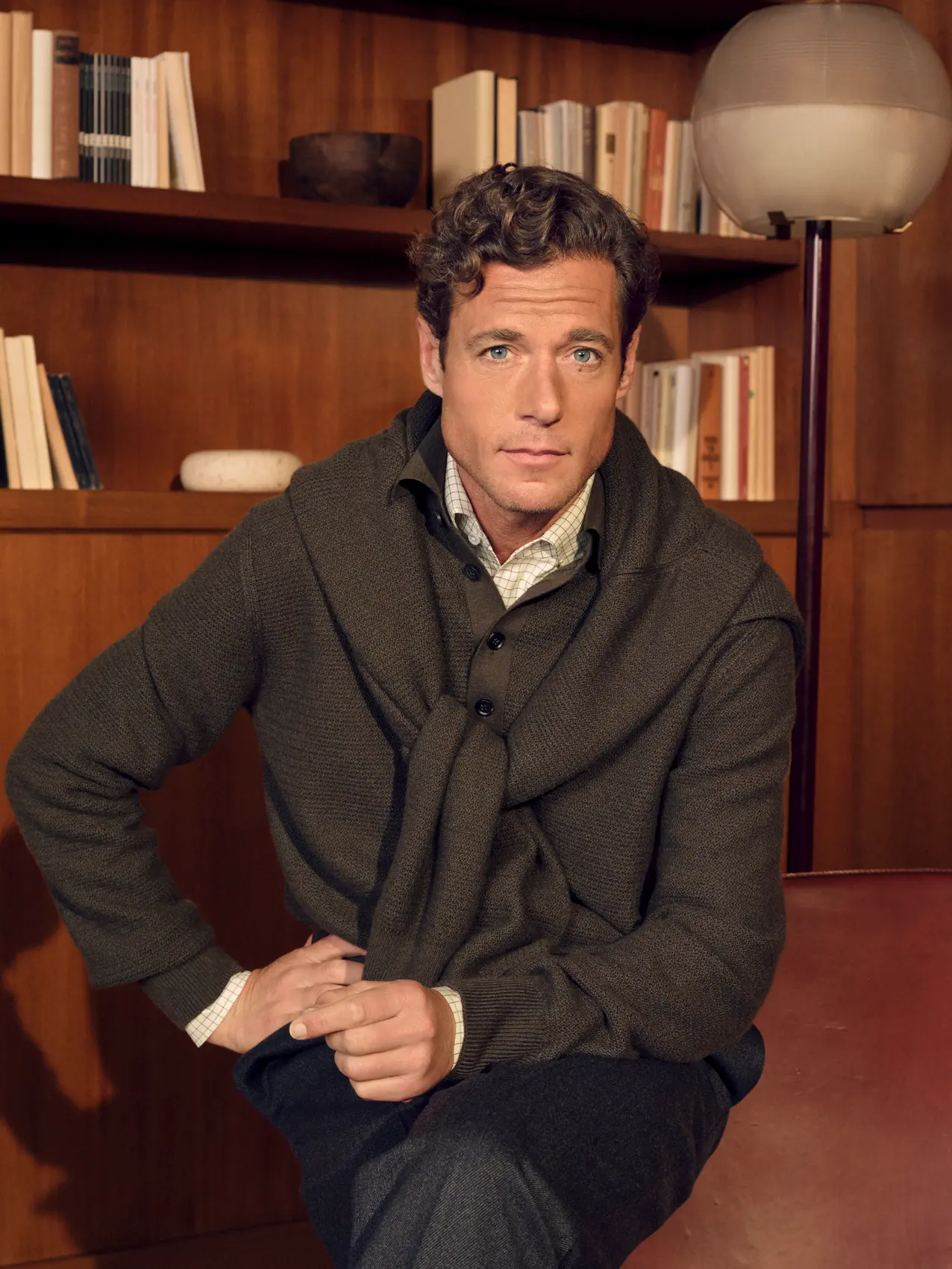 Man in an elegant look wearing an Oasi Cashmere polo in dark olive green with Cashseta crew neck in dark olive green, wool, silk and cashmere pants in dark grey, holding a Secondskin Weekender in dark brown, from the ZEGNA Fall/Winter 2026 collection.