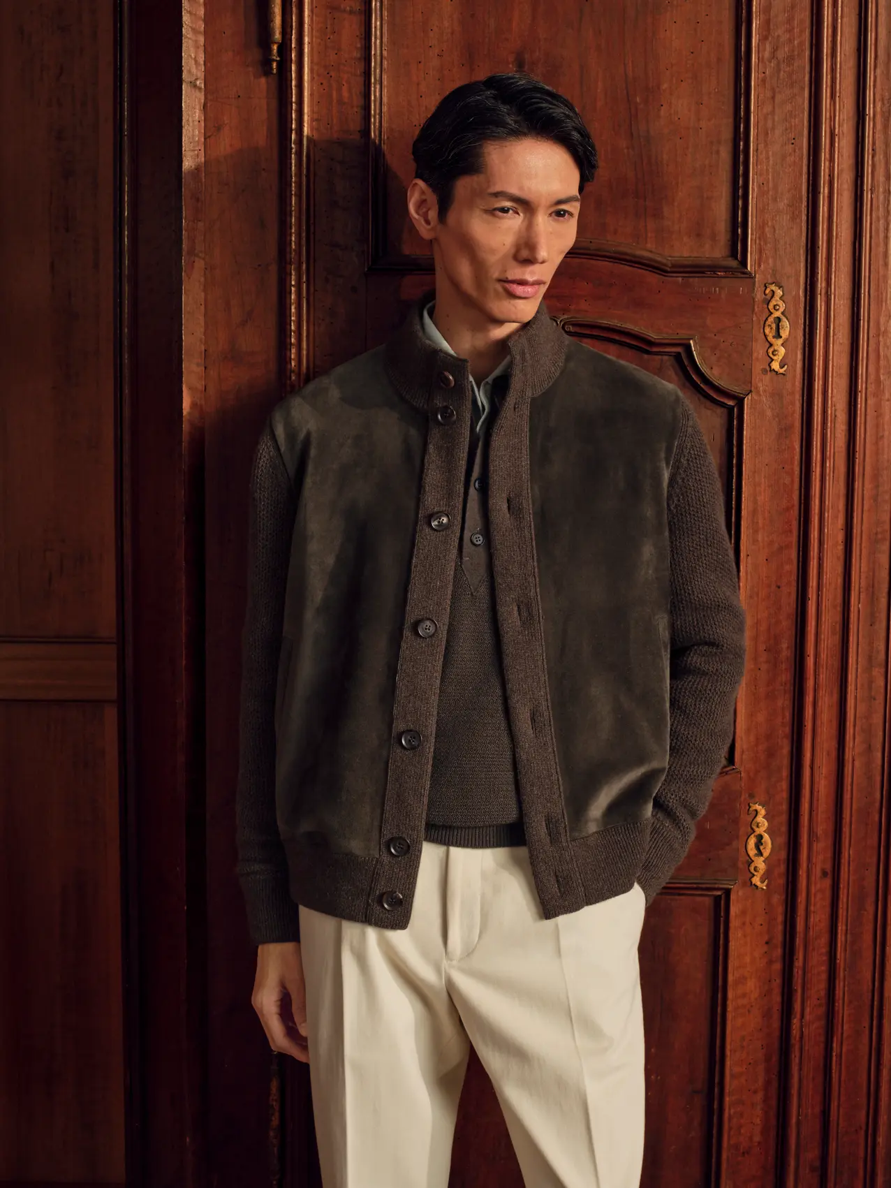 Man in an Oasi Cashmere Blouson in dark olive over an Oasi Cashmere Polo in dark olive and a Cashco Oxford Shirt in light green, styled with Cotton and Wool Pants in cream white and Triple Stitch Low Top Sneaker in dark olive Secondskin, from the ZEGNA Fall/Winter 2026 collection.