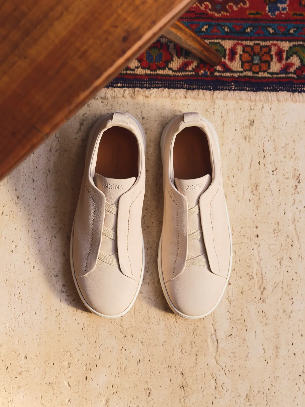Top view of the Triple Stitch sneakers in white grained calfskin with elasticated tongue and tonal white sole, from the ZEGNA Fall/Winter 2026 collection.
