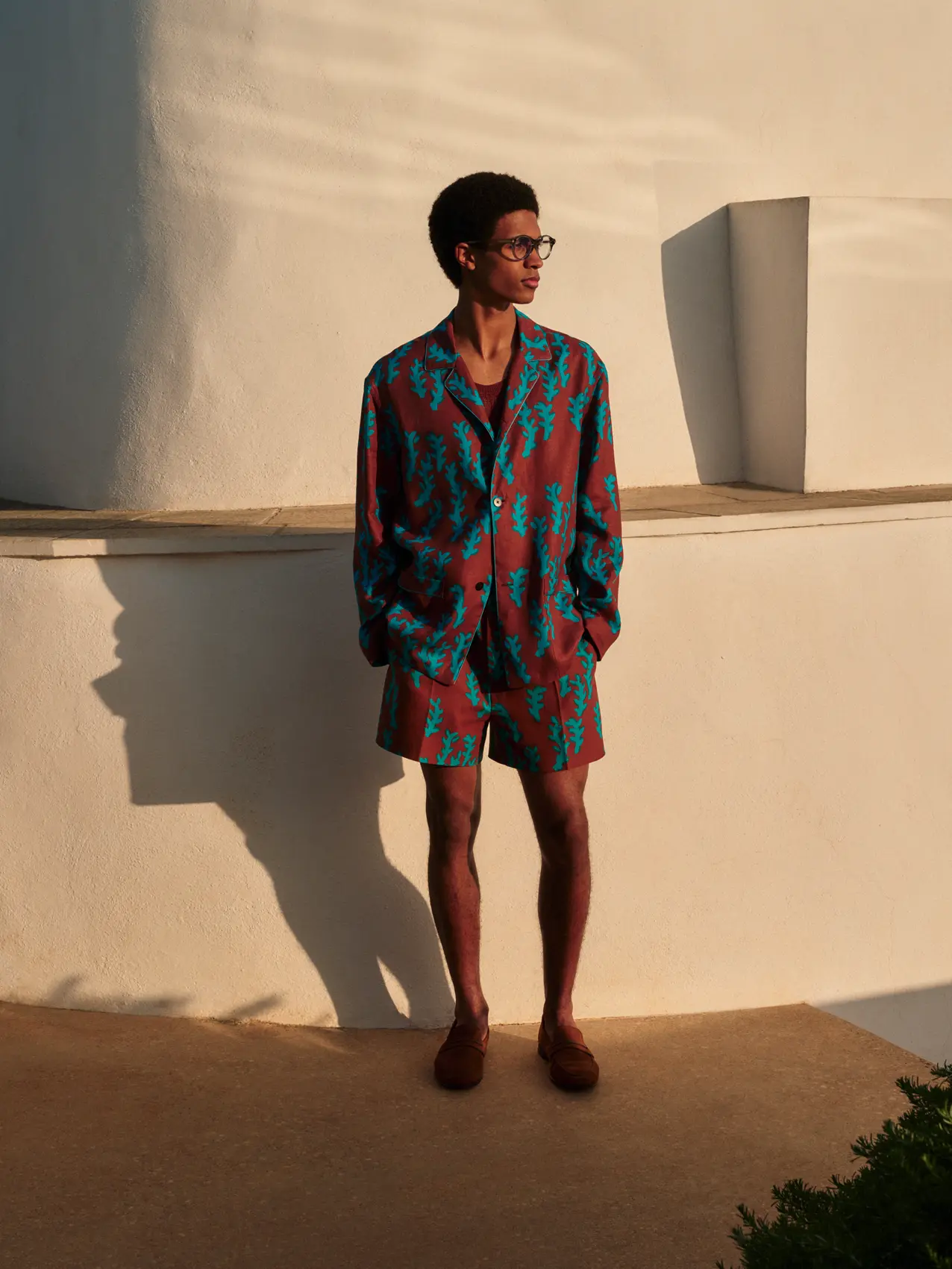 男士穿著 ZEGNA 鮮豔的印花夏季套裝，包括寬鬆紐扣襯衫和短褲。