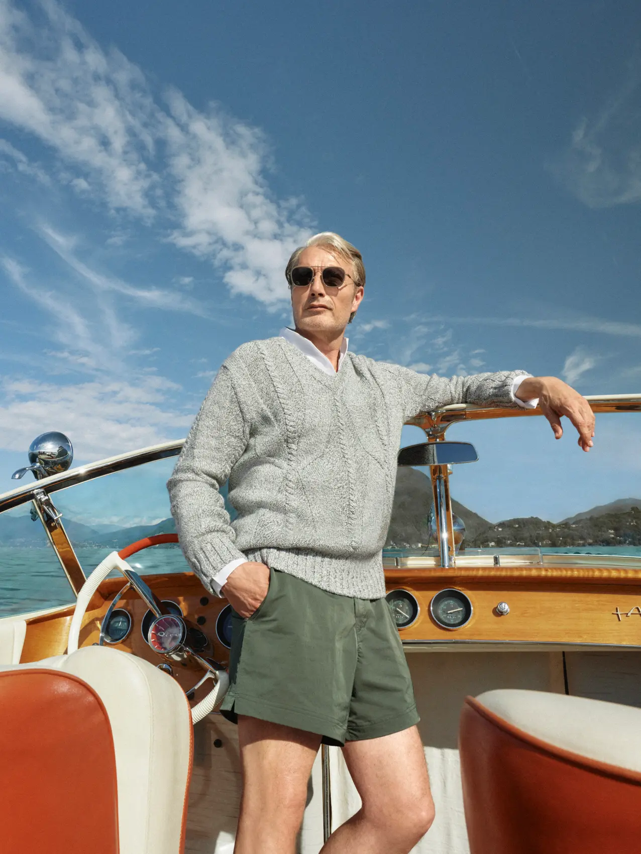 Mads Mikkelsen on a boat wearing a ZEGNA Spring Summer 2026 look featuring a V-neck sweater and the iconic Rio beachwear