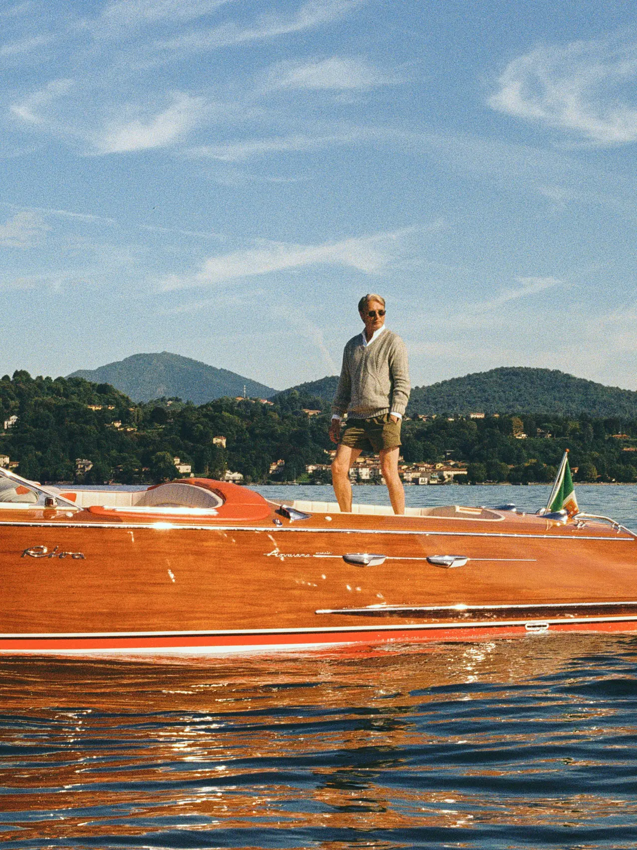 Mads Mikkelsen on a boat wearing a ZEGNA Spring Summer 2026 look featuring a V-neck sweater and the iconic Rio beachwear