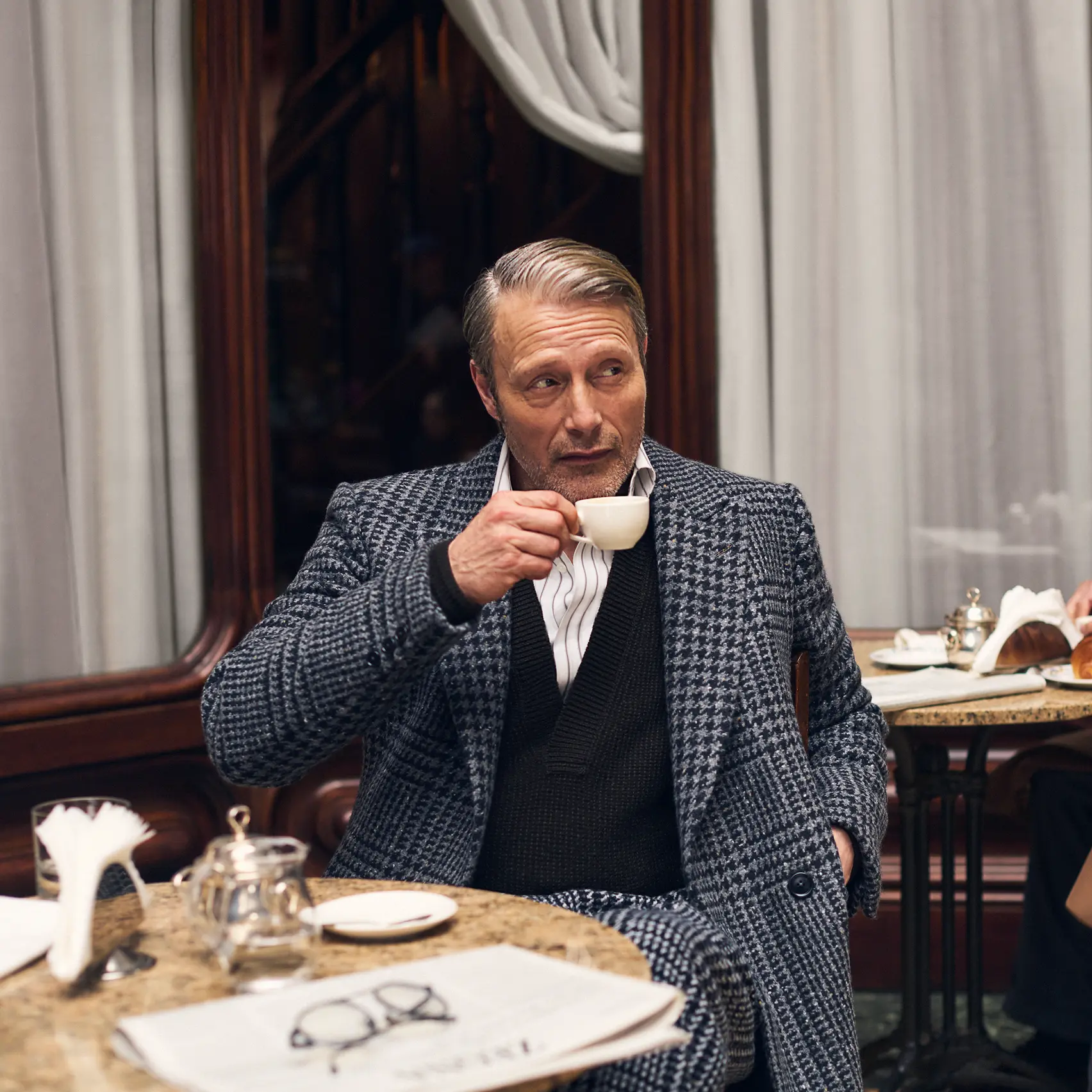 Mads Mikkelsen 坐在咖啡店,身著 ZEGNA FW25 Couture 系列的 Torino 風格精裁西裝。