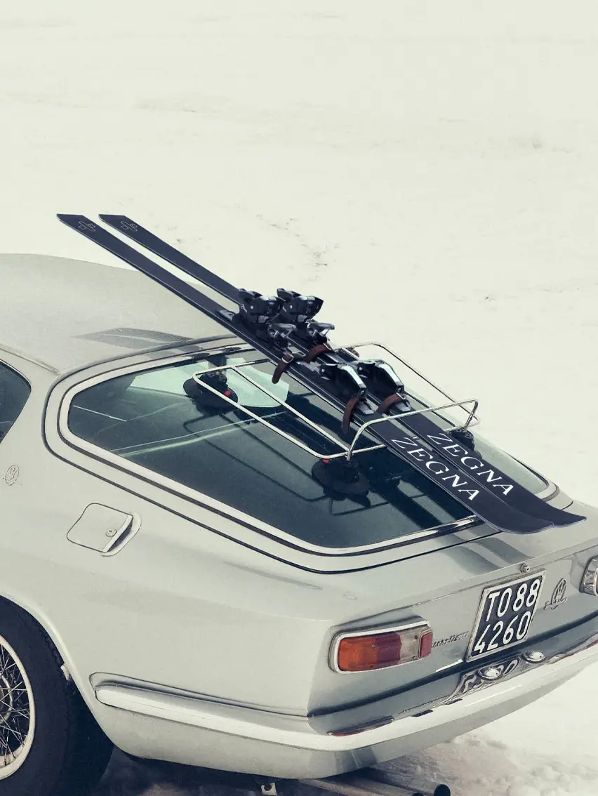 Sports car in a snowy landscape featuring ZEGNA skis, Fall Winter 2025 collection campaign.
