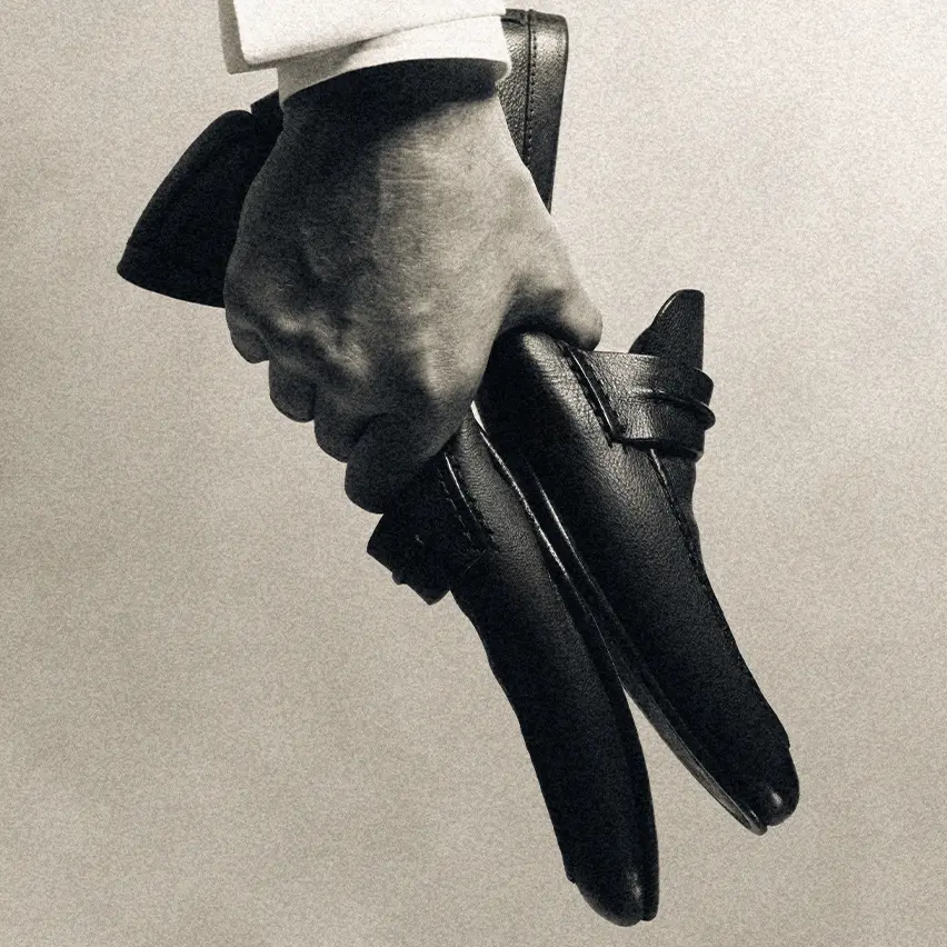 手握一雙 ZEGNA Mocassin 便鞋,展示其優雅的工藝。