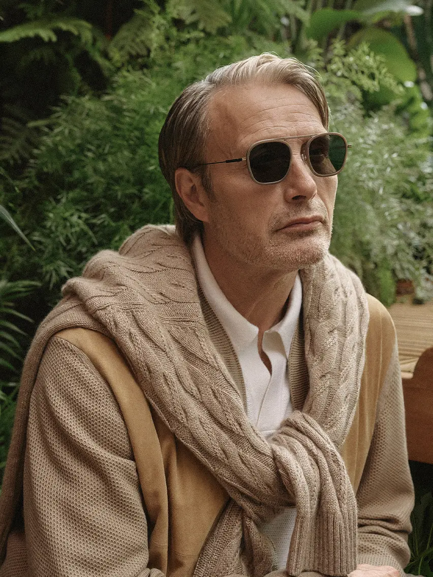 Mads Mikkelsen 身著 ZEGNA SS26 系列的山羊絨飛機䄛、輕盈針織圓領上衣，戴著同系列太陽眼鏡。