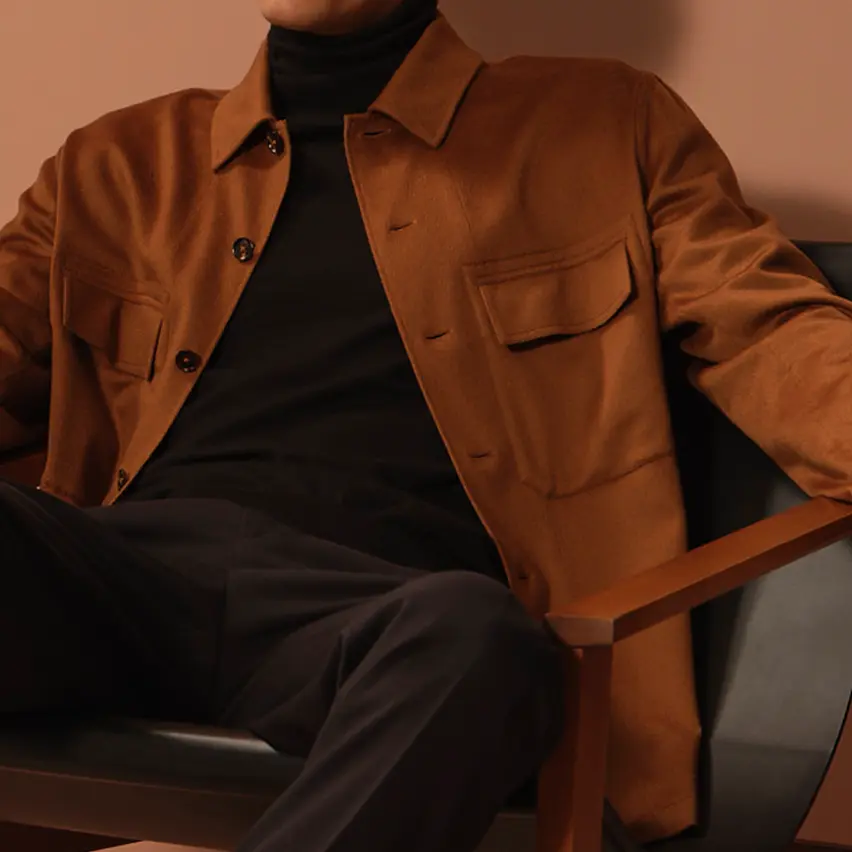 一位坐着的男士穿着 ZEGNA(杰尼亚)新款系列服装,黑色裤子搭配 Vicuña 色羊毛衬衫外套。