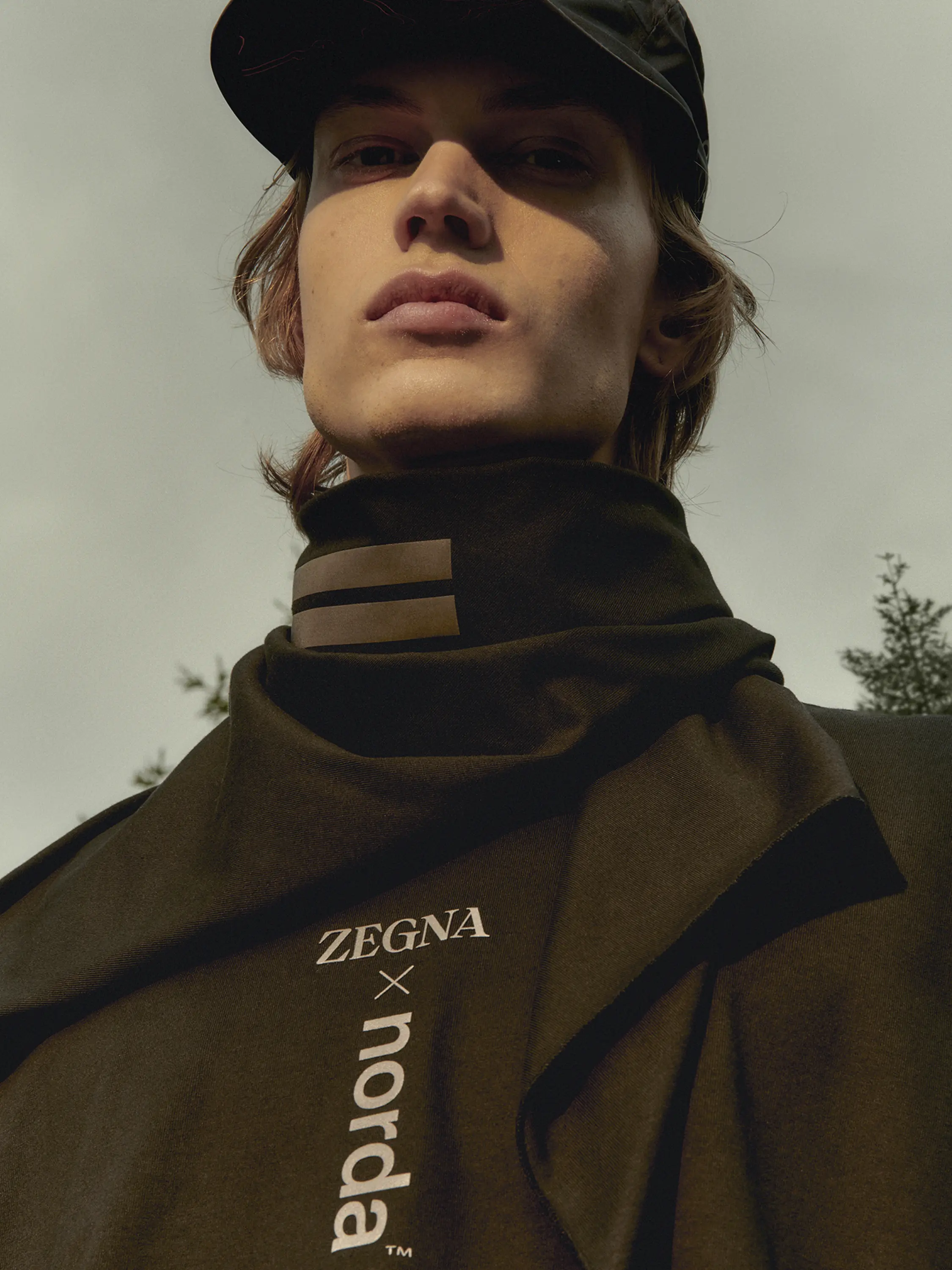 一位男士身着来自 Outdoor Collection 并带有 ZEGNA x Norda 徽标的黑色帽子、围脖和运动衫。