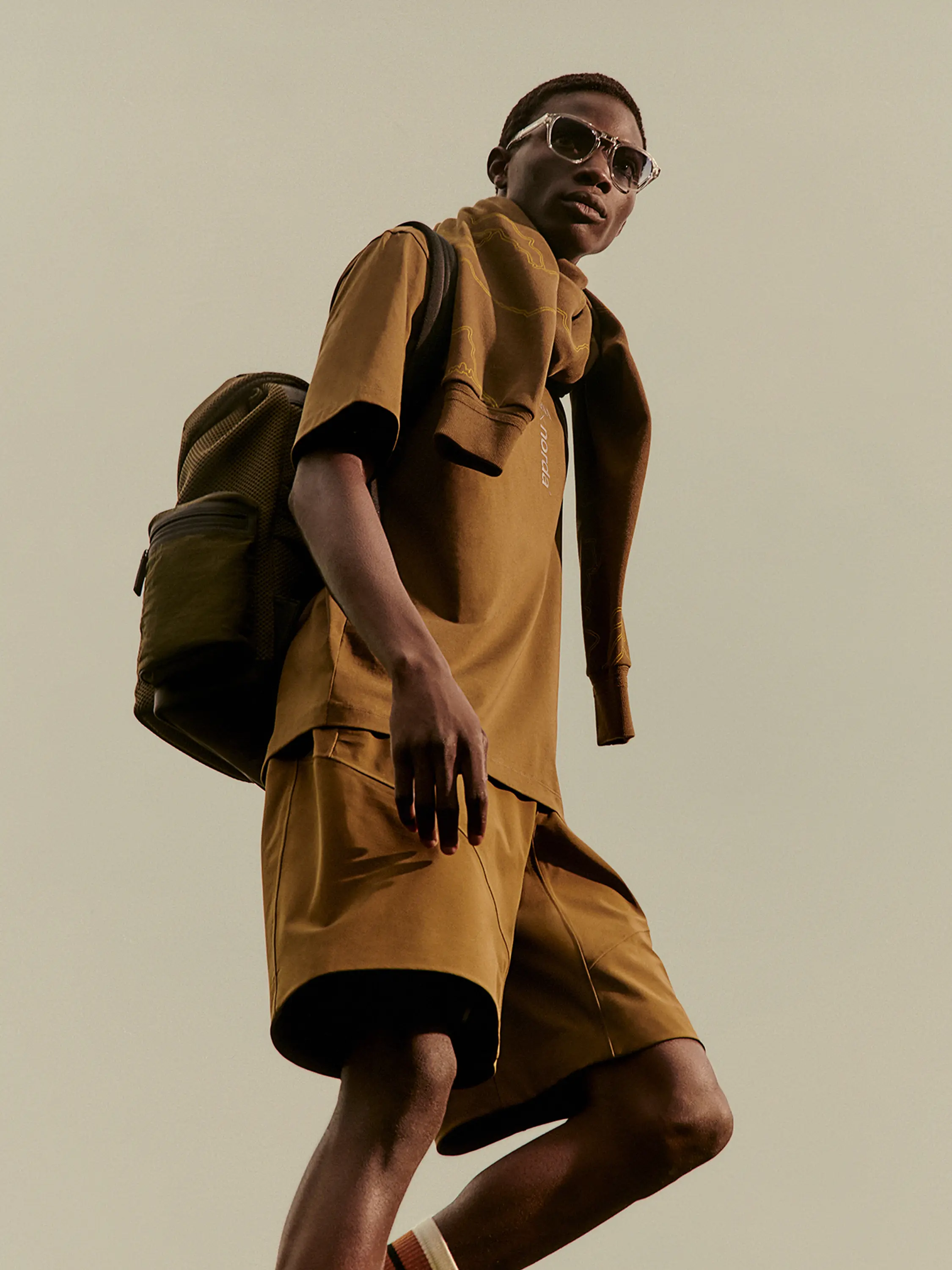 一位男士身着 ZEGNA(杰尼亚)与 Norda 合作推出的 Outdoor Collection 的太阳镜、棕色围巾和运动衫。