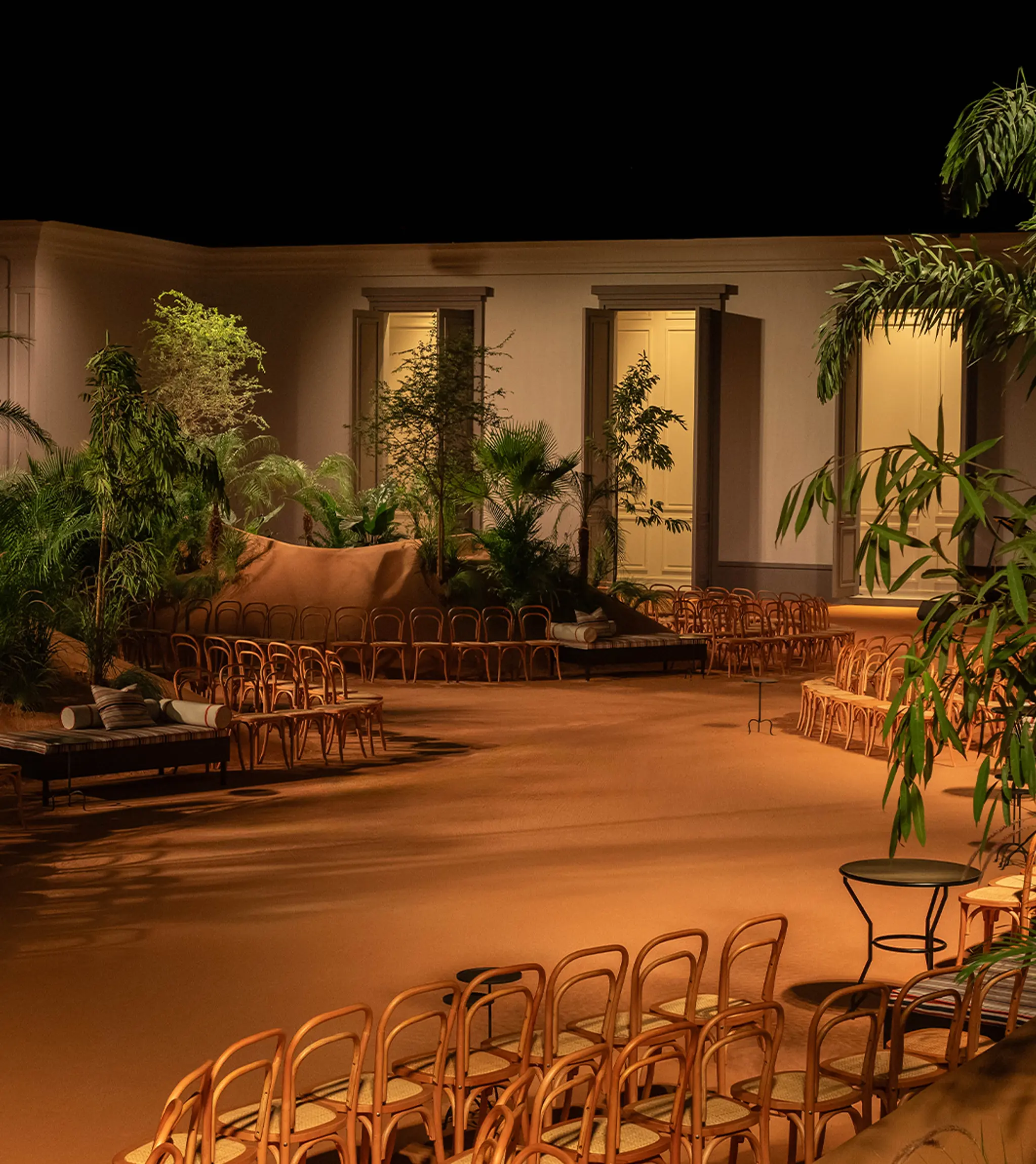 A location set with rattan chairs and tropical plants evoking a desert oasis.