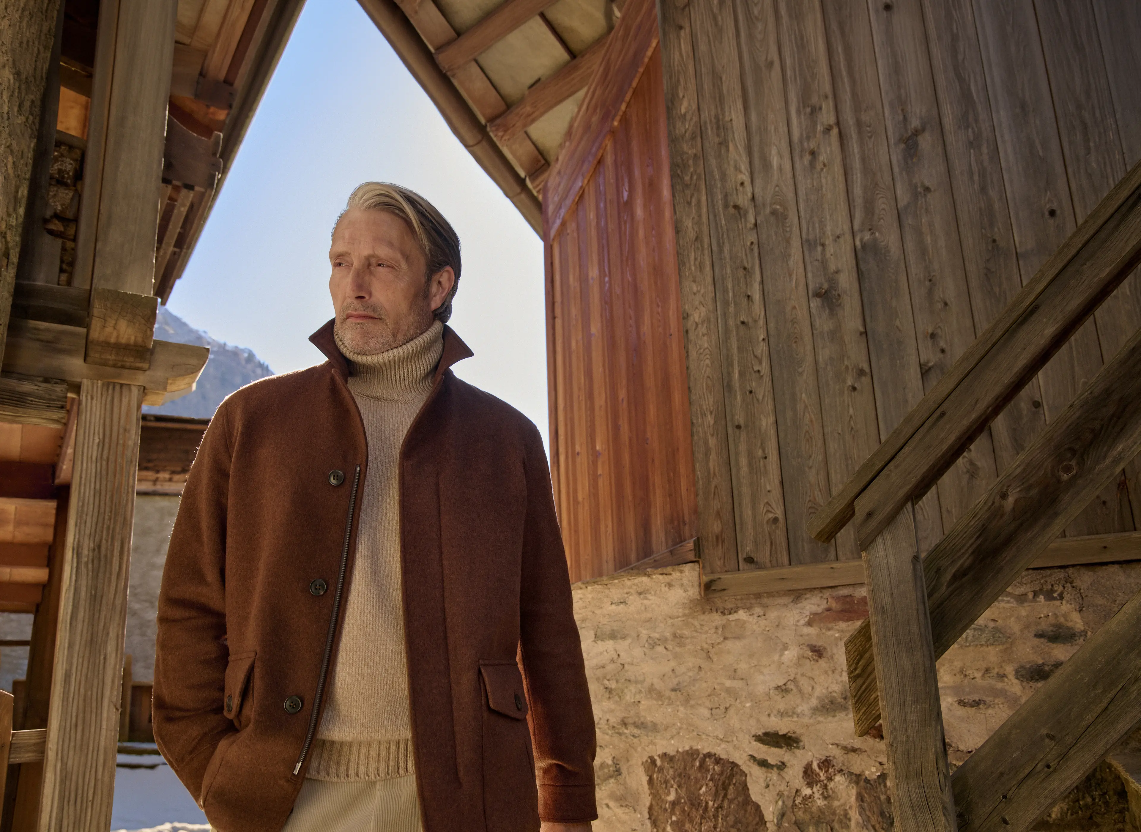 Mads Mikkelsen 身着新款 Falcon 夹克，甄选锈棕色 Oasi Cashmere Elements 面料打造，纽扣与拉链双重开合设计，内搭奶油色高领针织衫，演绎 ZEGNA（杰尼亚）2026 秋冬系列。