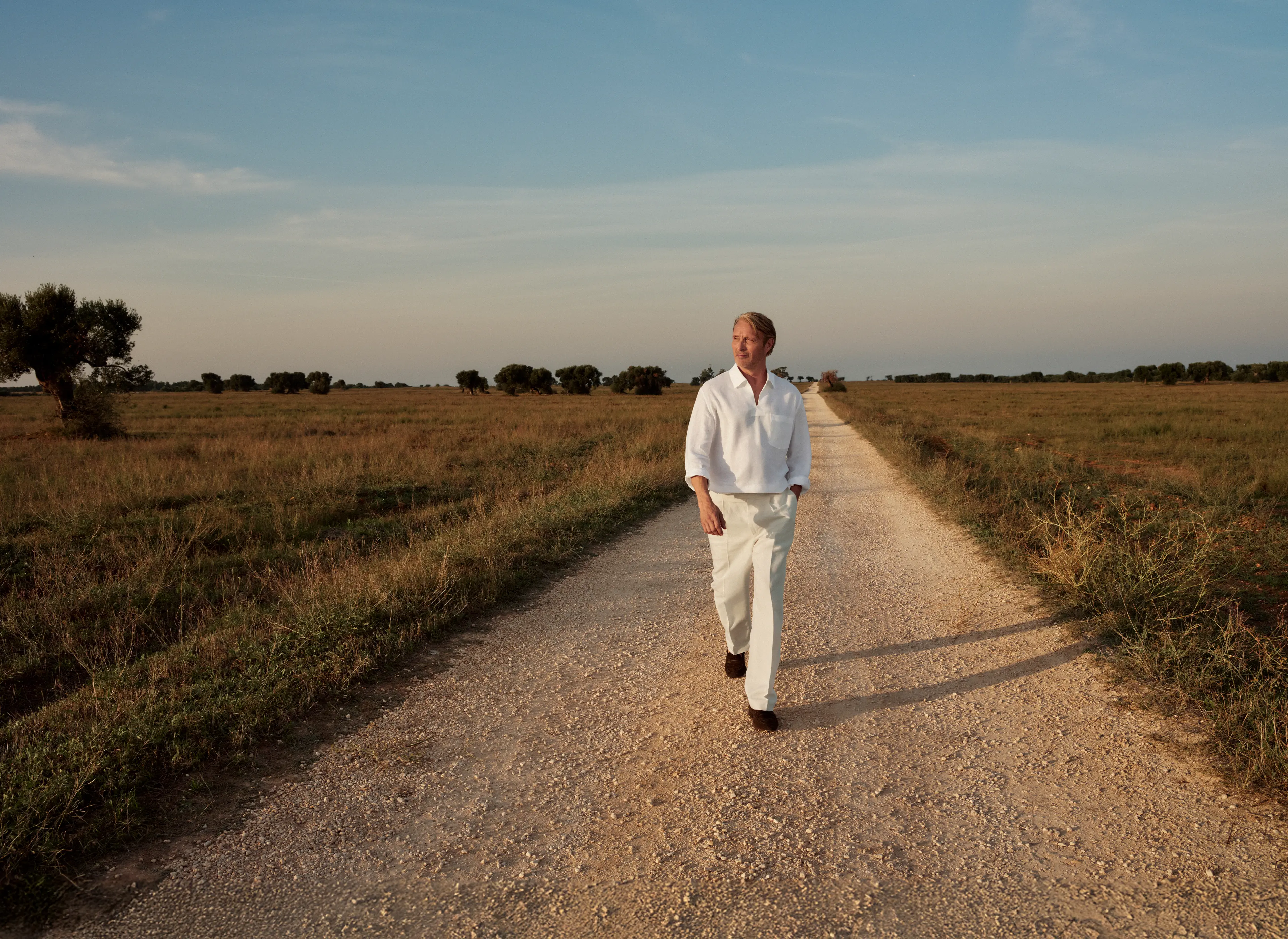 Mads Mikkelsen wearing a refined linen outfit paired with suede loafers from the ZEGNA SS25 collection.