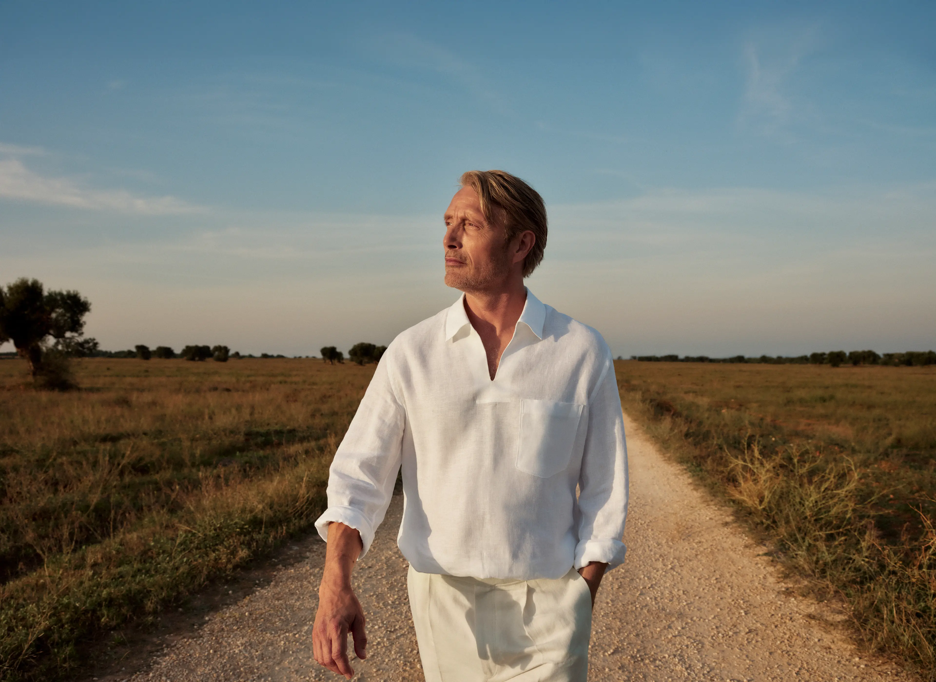 Mads Mikkelsen wearing a refined linen outfit paired with suede loafers from the ZEGNA SS25 collection.