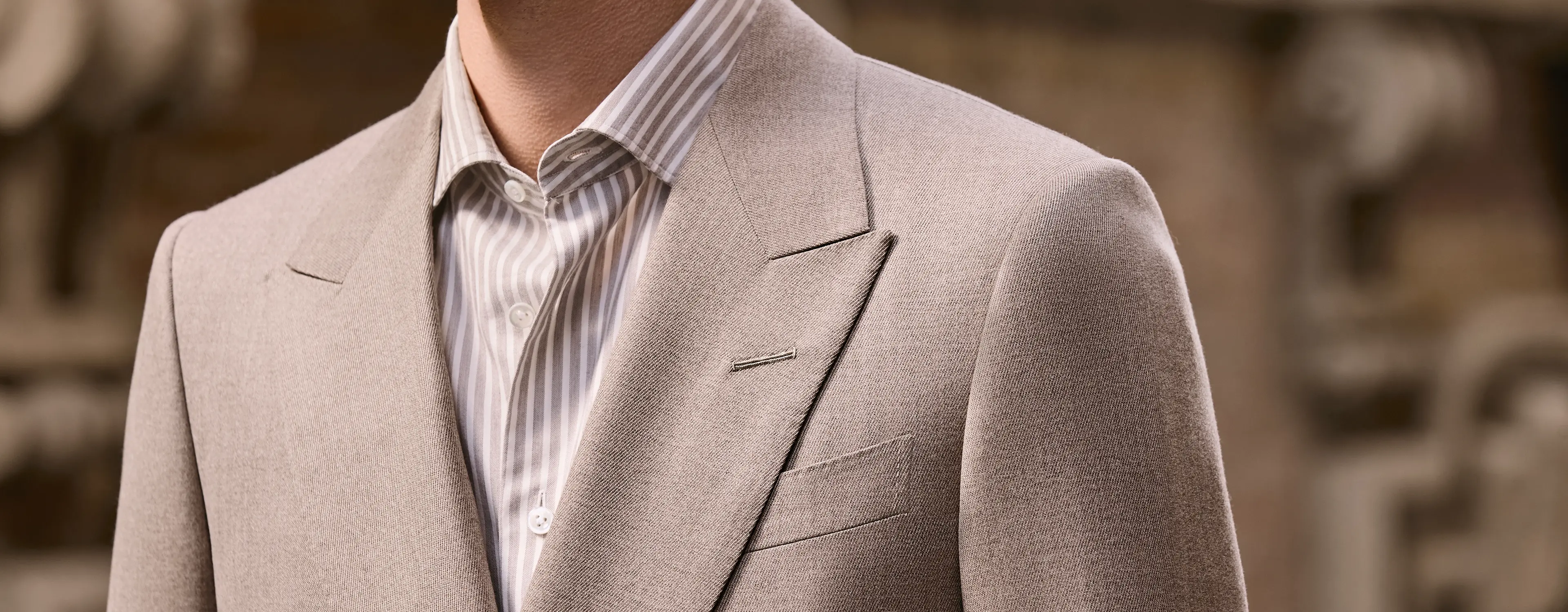 ZEGNA(杰尼亚)米色西装夹克特写,搭配条纹衬衫与叠穿针织衫。