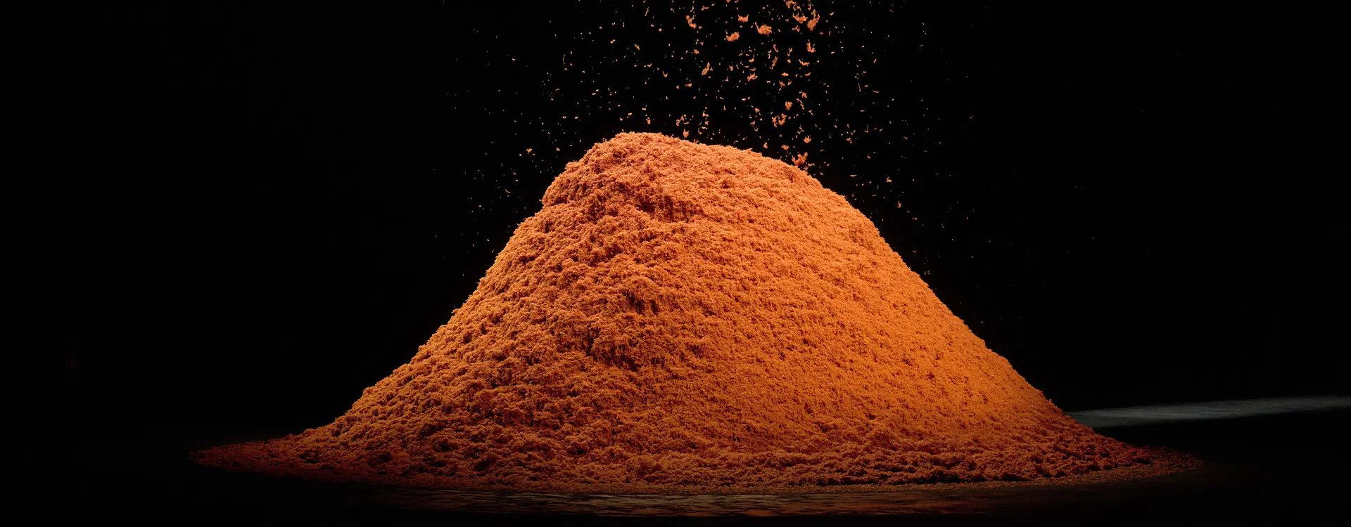 A pile of vibrant orange cashmere fibers arranged neatly against a black background.