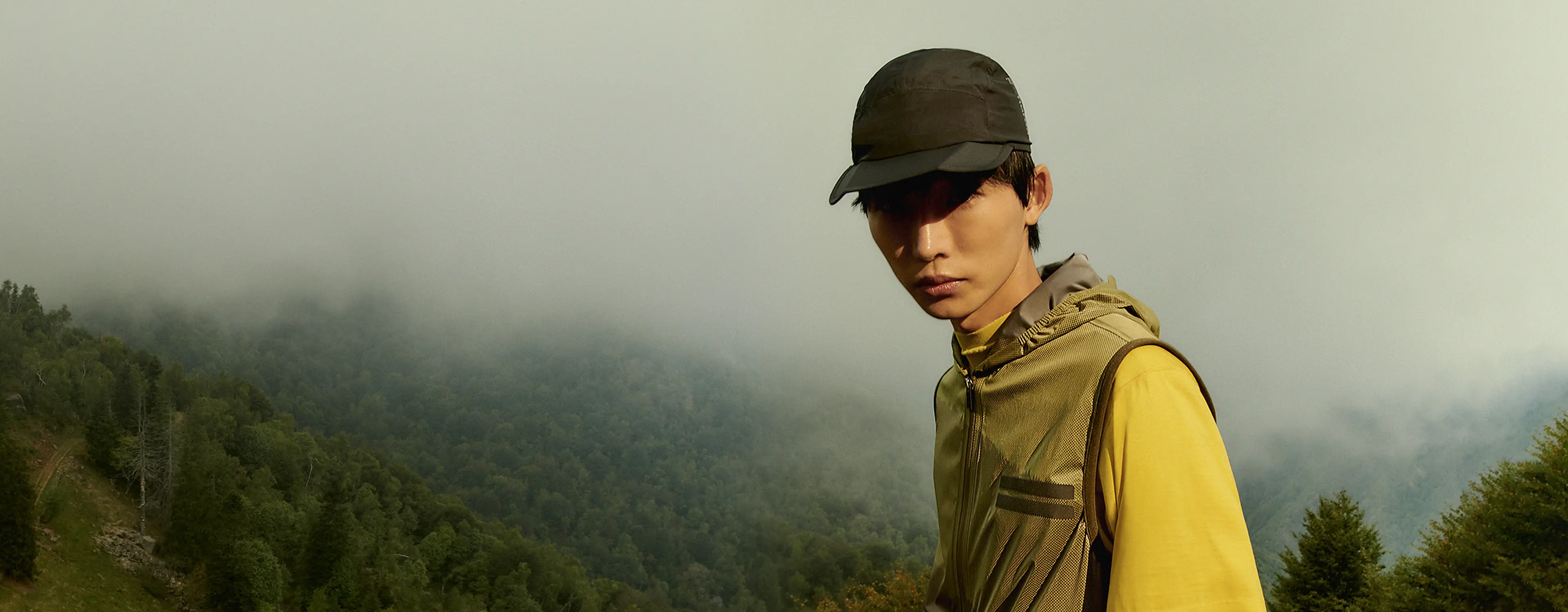 一位在大自然中、身着 ZEGNA (杰尼亚)Outdoor Collection 徒步旅行装备的男士站在岩石上。
