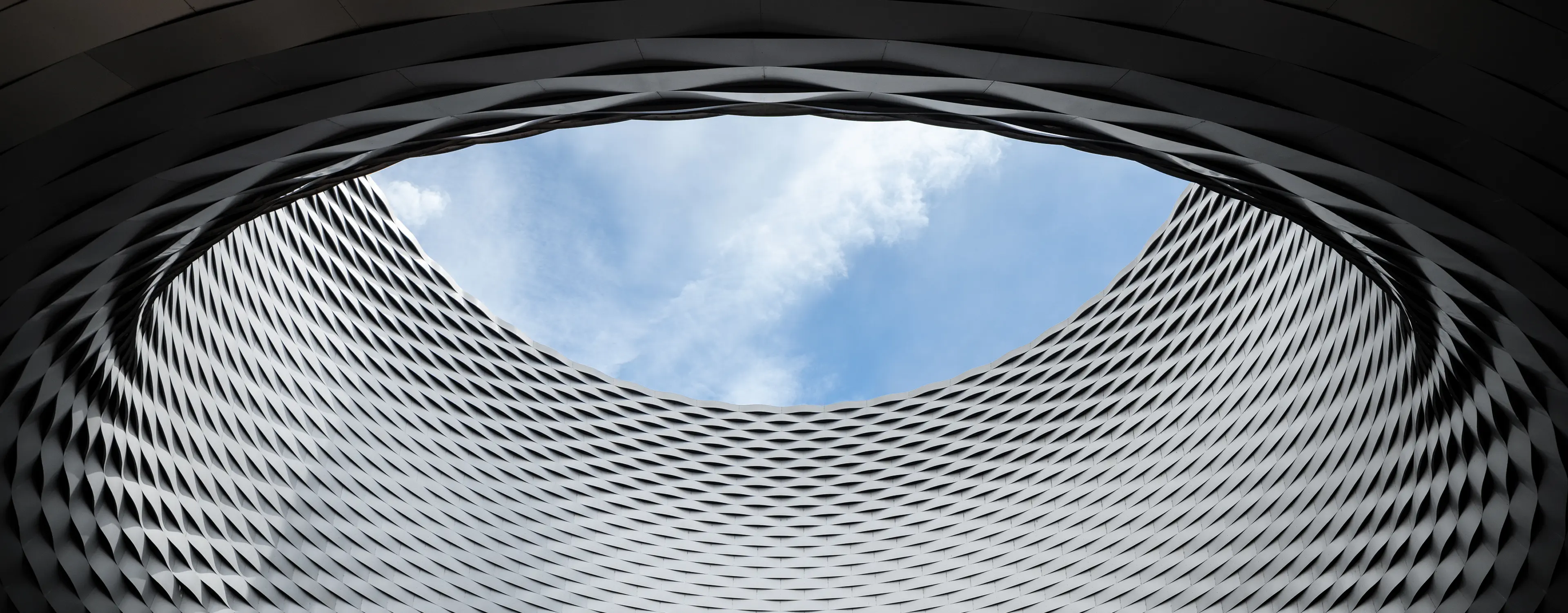 Interior view of the Art Basel venue, showing the dramatic circular opening and textured architectural structure of Messe Basel.