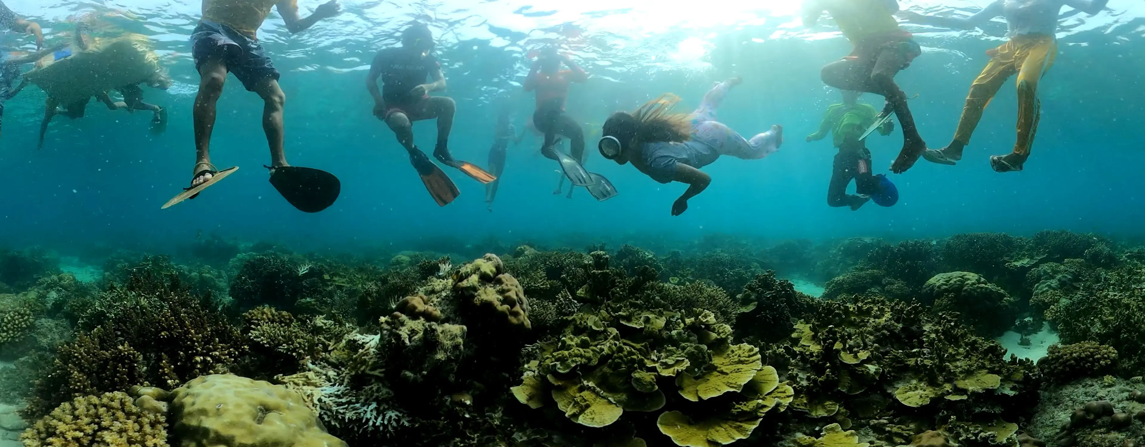 People snorkeling above a coral reef during a community marine conservation activity in the Philippines.