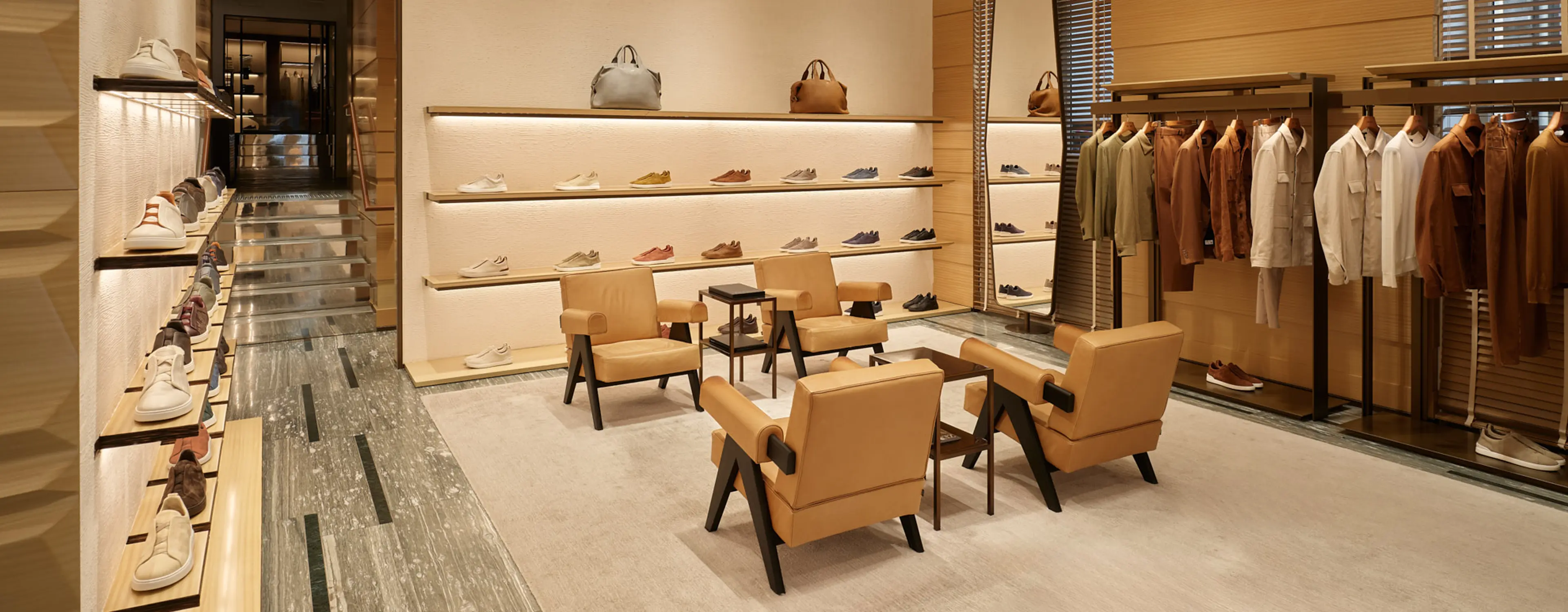 Interior of ZEGNA luxury boutique with shoes, bags, and clothing elegantly displayed on shelves.